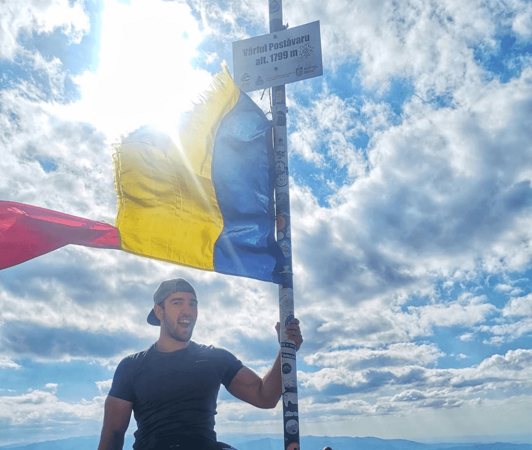 Photo of Buiuc Dragos holding a romanian flag on the top of the mountain, used in context of smrtPhone services.